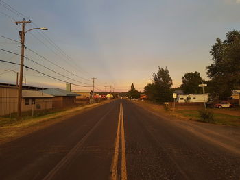 Road by electricity pylon against sky