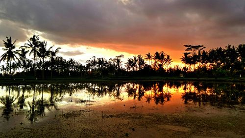 Scenic view of lake against cloudy sky at sunset