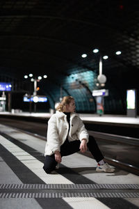 Woman standing on railroad station platform at night