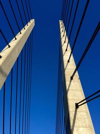 Low angle view of suspension bridge against clear blue sky