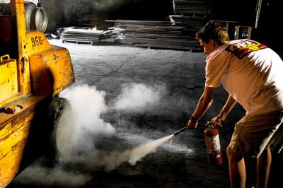 Man using fire extinguisher on vehicle