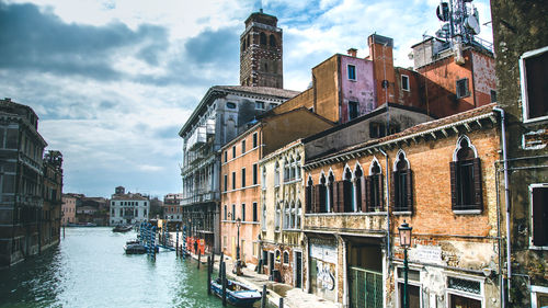 Canal amidst buildings in city against sky