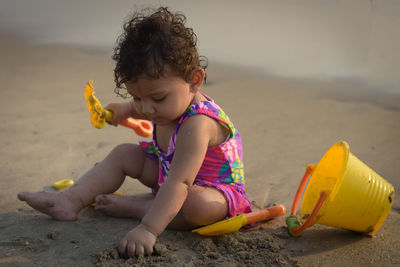 Side view of young woman sitting on sand at beach