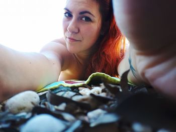 Close-up portrait of young woman lying at beach