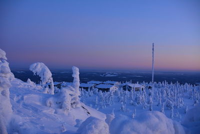 Snow covered landscape against sky during sunset
