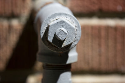 Water pipe painted grey, jutting out from a red brick house