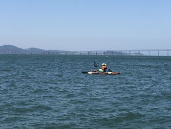 Men on boat in sea against clear sky
