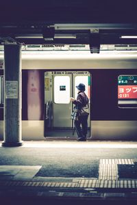 Rear view of man walking on illuminated railroad station platform