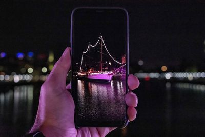 Person holding mobile phone in river at night