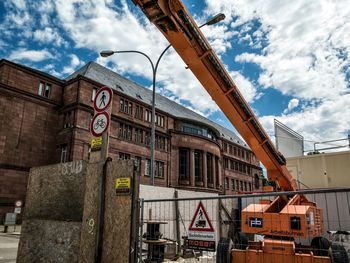 Road sign at construction site in city against sky