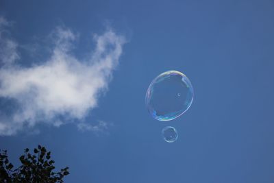 Low angle view of bubbles against blue sky