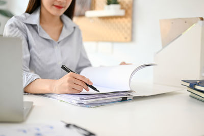 Midsection of businesswoman using laptop on table