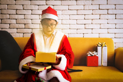 Woman wearing hat sitting against wall at home