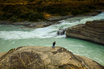 High angle view of man standing on rocks by sea