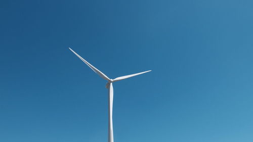 Low angle view of windmill against clear blue sky