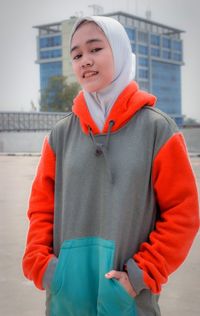 Portrait of smiling girl standing in city during winter