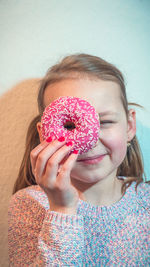 Close-up of girl holding donut in front of face