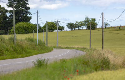 Road amidst field against sky