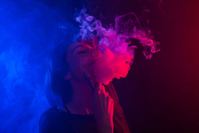 Close-up of man smoking against black background