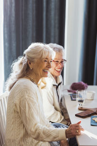 Happy elderly female friends sitting at retirement home