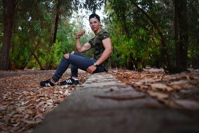 Full length of man sitting on sidewalk in forest