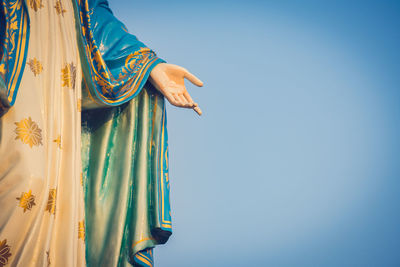 Low angle view of woman standing against blue sky