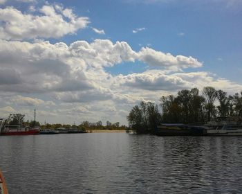 Scenic view of calm river against cloudy sky