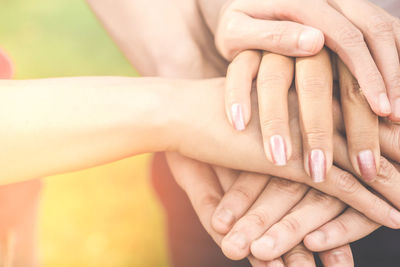 Cropped image of friends stacking hands outdoors