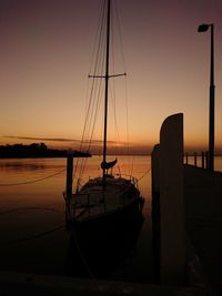 Silhouette boat sailing in sea against sky during sunset