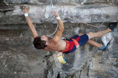 Midsection of man with arms raised on rock