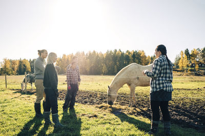 Female instructor explaining farmers about horse at farm
