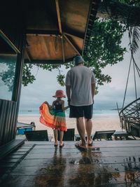 Father and little daughter holding hands at the beach resort. view from behind.