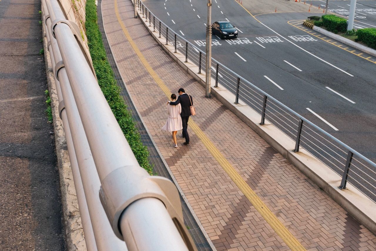 high angle view, full length, real people, walking, railing, outdoors, road, day, railroad track, lifestyles, men, water, one person, city, people