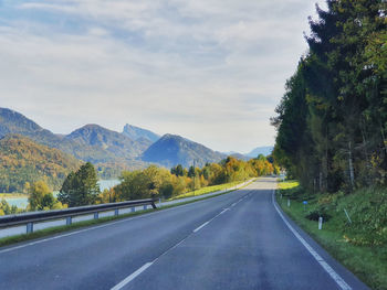 Road amidst trees and mountains against sky