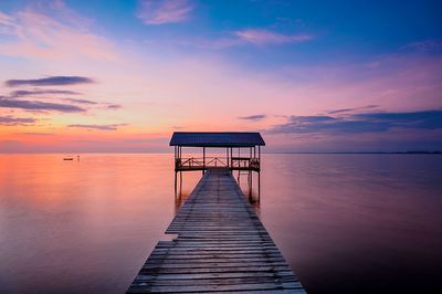 Pier over sea against sky during sunset