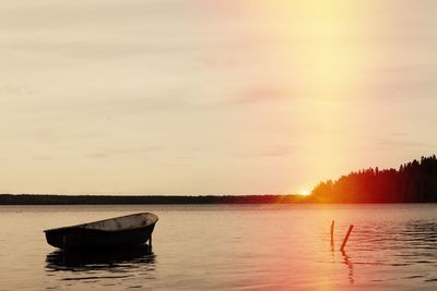 Boat in lake against sky during sunset