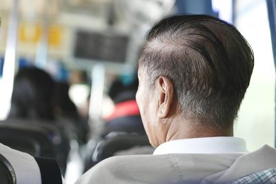 Rear view of senior man sitting in bus