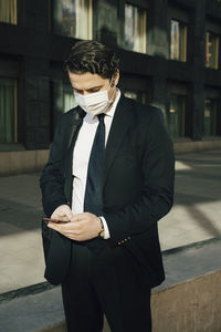 Businessman with face mask using smartphone