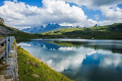 Scenic view of mountains by calm lake against cloudy sky