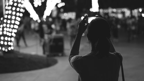 Rear view of woman taking picture at night