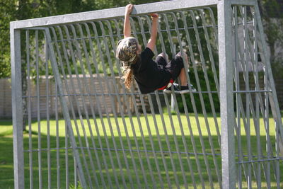 Rear view of boy climbing on metallic goal post