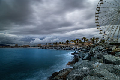 View of amusement park by sea against sky