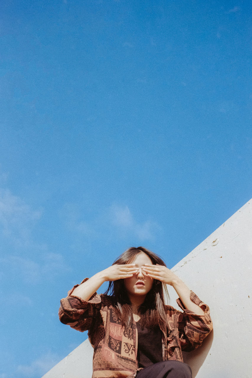 one person, sky, young women, leisure activity, lifestyles, copy space, young adult, blue, front view, real people, portrait, women, nature, day, looking at camera, low angle view, beauty, hair, hairstyle, beautiful woman, outdoors