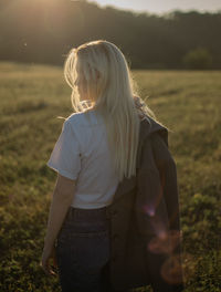 A young woman standing in a field during sunset