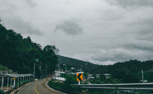 Road by trees against sky