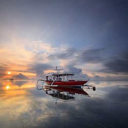 Boats in sea against sky during sunset