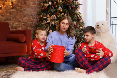 Happy family mother with sons on christmas morning in pajamas near christmas