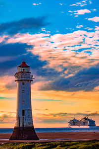 Lighthouse by sea against sky during sunset