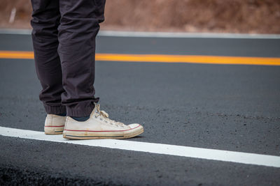 Low section of man standing on road