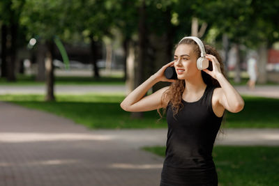 Young female runner listening music at park